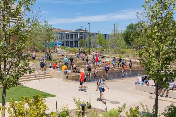 People are sitting around and jumping in a splash pad at the Gene Leahy Mall, a public space in Omaha.