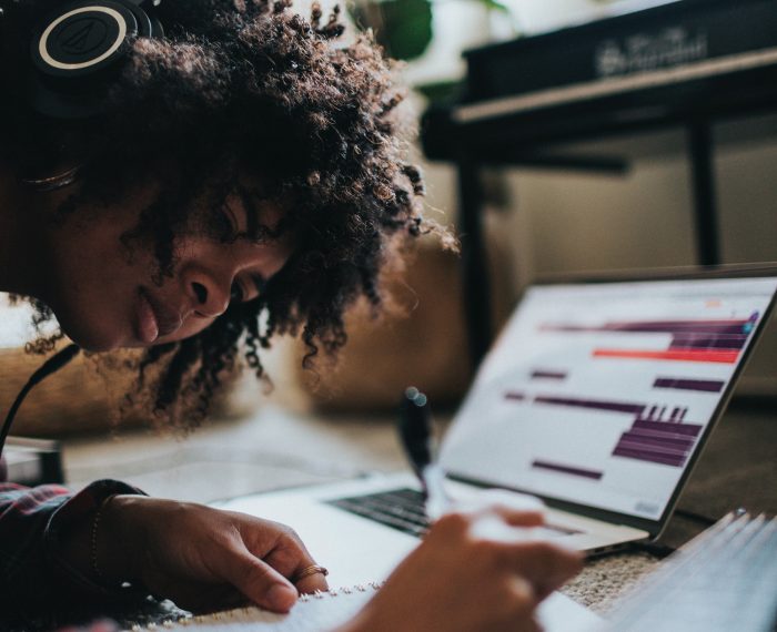 A woman with headphones on working on grant writing at a desk