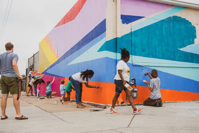 People painting a mural on the side of a building
